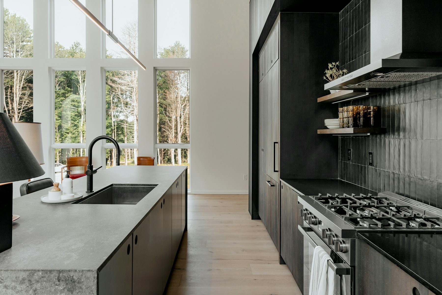 Bright modern kitchen with black cabinetry, large island and floor-to-ceiling windows